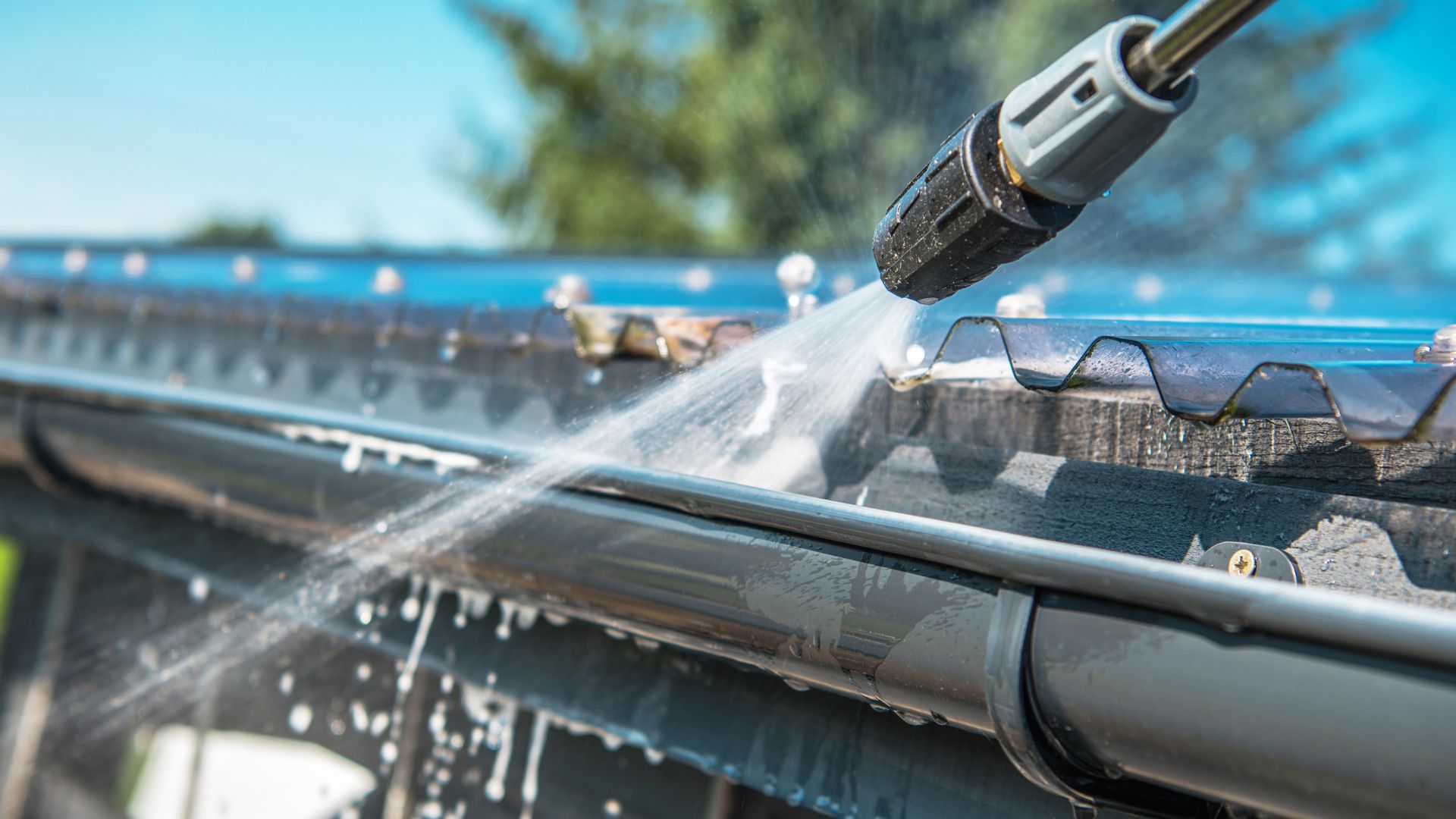 Pressure washer spraying water on a gutter to clean debris